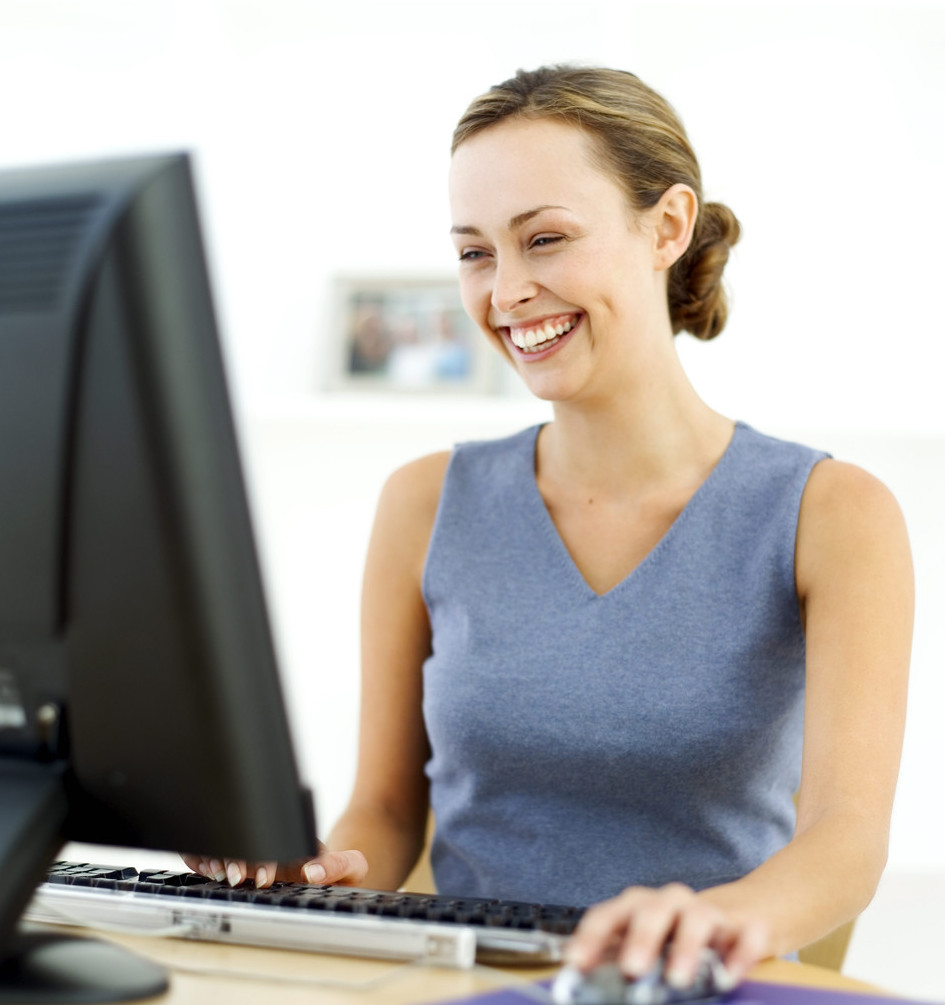 Young Woman Sitting in Front of a Computer and Laughing